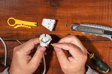 Bir çatala kablo döşemek. Elektrikçi fişi elektrik kablolarına bağlıyor..