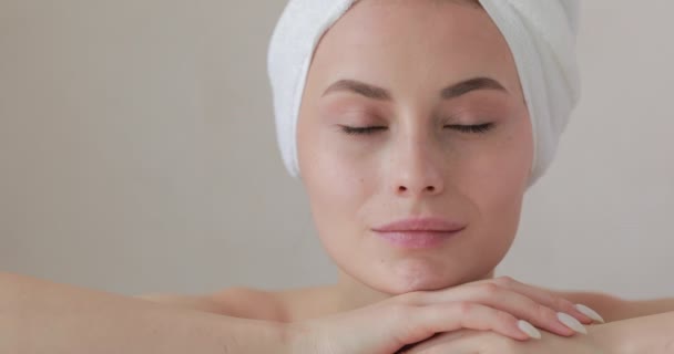 Hermosa mujer joven con toalla en la cabeza después de la ducha aislada sobre fondo blanco. Mujer feliz con piel fresca y pura cuidando la salud y el cuerpo. — Vídeos de Stock