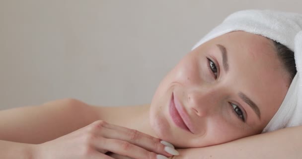 Blisko ładna młoda kobieta z ręcznikiem kąpielowym na głowie uczucie świeżości po porannym prysznicu. Szczęśliwy model z naturalnym pięknem pozowanie przed kamerą. — Wideo stockowe
