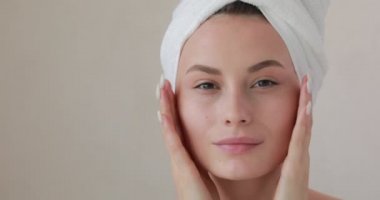 Çekici bir model, sabah ameliyatlarından sonra taze cildinin tadını çıkarıyor. Genç bir kadın parmaklarıyla yüzüne dokunuyor. Spa tedavisi ve refah kavramı.