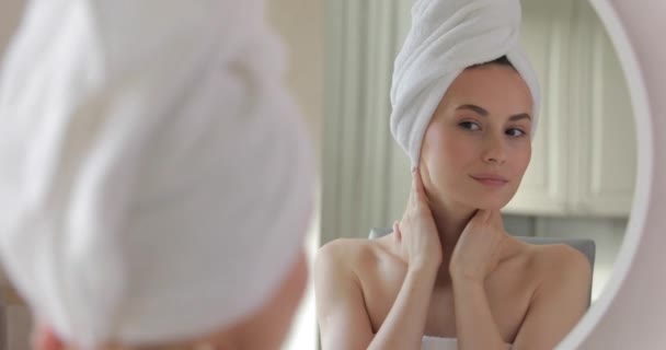 Impresionante joven con los hombros desnudos de pie en el baño brillante y haciendo masaje facial con los dedos. Mujer feliz satisfecha con el estado de su piel. — Vídeo de stock