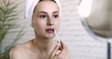 Banyo havlusuna sarılı, duştan sonra ruj süren çekici bir kadının portresi. Evde sabahları makyaj yapan genç bir bayan..