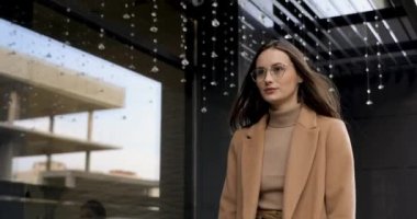 Ceketli ve gözlüklü güzel bir esmer sokakta yürüyor ve ciddi bir yüz ifadesiyle gezici ekrana bakıyor. Modern cihazın yardımıyla acil sorunları çözen düşünceli bir kadın..