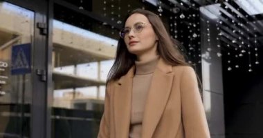 Kendine güveni tam, uzun saçlı, caddede yürüyen ve akıllı telefon kullanan güzel bir bayan. Gözlüklü ve sonbahar ceketli genç bir kadın modern aletlerle temiz havada vakit geçiriyor..