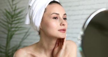 Mutlu genç bayan sabah vaktini güzellik prosedürü için tuvalette geçiriyor. Havluya sarılmış bir kadın evde cildiyle ilgileniyor..