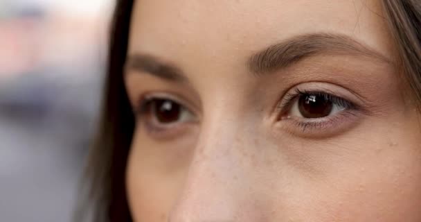 Atractiva joven morena sonriendo y mirando a la cámara mientras está de pie en la calle. Foco de ojos marrones oscuros. Concepto de positividad y feminidad. — Vídeos de Stock