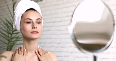 Çıplak omuzlu çekici bir kadın deri kaldırmak için boynuna masaj yapıyor. Mutlu kadın sabah saatlerinde güzellik prosedürlerinden zevk alıyor..