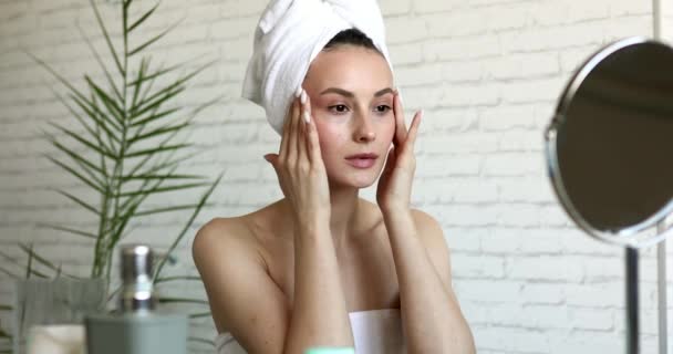 Schöne junge Brünette mit nackten Schultern bei einer Massage unter den Augen im Badezimmer. Sensibler Teil der Gesichtshaut. Heimische Wellness-Behandlungen. — Stockvideo