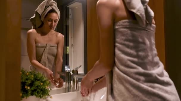 Fantastisk ung dam i frotté handduk tvätta händerna med tvål i vit handfat. Reflektion i spegel på modernt badrum. Begreppet morgon rutin och hygien. — Stockvideo