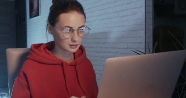 Evde modern dizüstü bilgisayarda çalışan olumlu bir kadın.