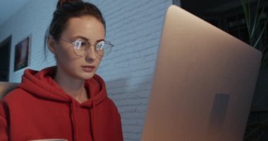 Güzel bir kadın masada oturuyor ve dizüstü bilgisayarla çalışıyor.