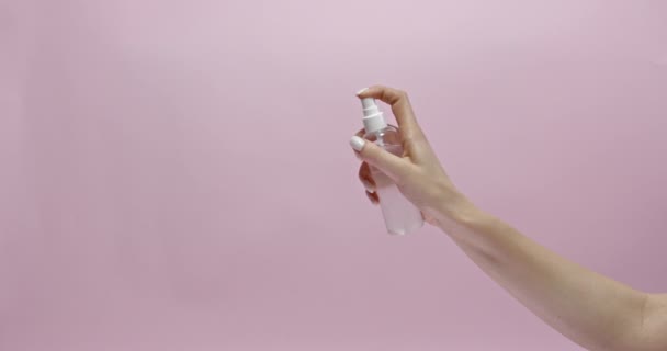 Person drückt Antiseptikum aus Flasche über rosa Hintergrund — Stockvideo