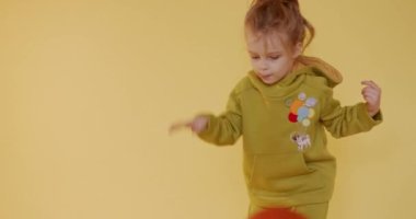 Stüdyoda sarı arka planda kırmızı topla oynayan sarı saçlı çekici küçük çocuk. Oyuncak atan ve yakalayan sevimli çocuk..