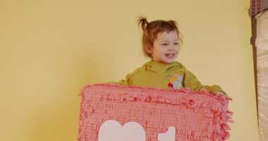 İki at kuyruklu, kalbi sosyal medyanın simgesi gibi gösteren şirin bir bebek. Sarı stüdyo geçmişi. Moda içeriği ve günlük tutma kavramı.