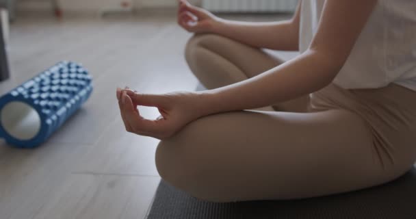 Close up of young female in activewear sitting on yoga mat in lotus pose. Woman having meditation session during domestic workout. Sport concept. — Αρχείο Βίντεο