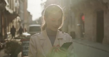 Güzel bir genç bayan boş zamanlarında modern akıllı telefon kullanıyor. Güzel esmer, şık günlük kıyafetler giyiyor. Teknoloji konsepti.