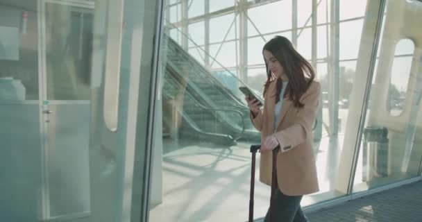 Mulher Negócios Elegante Andando Com Mala Perto Aeroporto Usando Smartphone — Vídeo de Stock