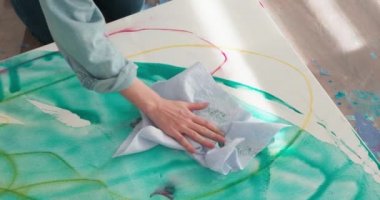 Çalışma alanında yerde otururken kadın ressamın tuvale soyut desenler çizmesine yakın çekim. Başyapıt yaratmanın modern tekniği.