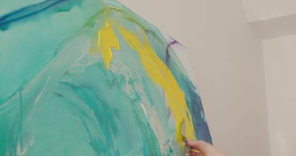 Talentierte Künstlerin trägt gelbe Farbe mit Spachtel auf abstraktes Muster auf. Junge Frau zeichnet auf Staffelei am Arbeitsplatz. Nahaufnahme. — Stockvideo