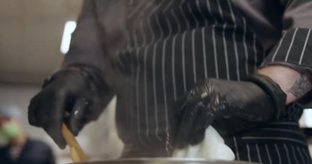 Manusia menggunakan spatula kayu saat membuat keju dalam air panas — Stok Video