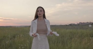 Sahada dikilirken beyaz gömleğini çözen hoş bir kadın. 