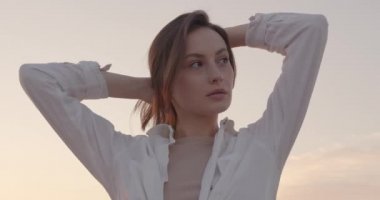 Dışarıdaki dalgalı saçlarına dokunan sevimli kadın.