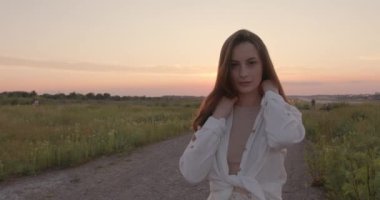 Gün batımında tarlada poz veren şefkatli kadın