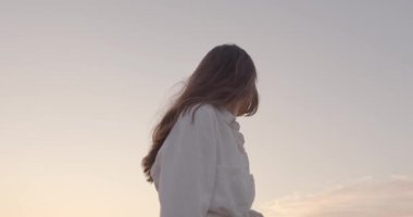 Çekici bir kadın yeşil alanda yaz günbatımının tadını çıkarıyor.