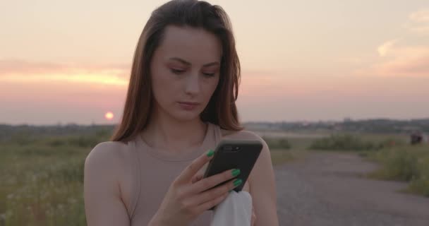 Mujer atractiva usando teléfono móvil en el campo — Vídeos de Stock