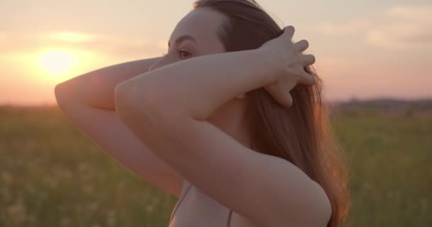 Charmante Frau steht bei Sonnenuntergang im Sommer auf dem Feld — Stockvideo