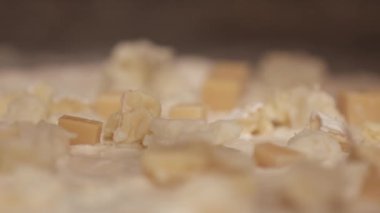 Aşçı pizza tabanına çeşitli peynirler ekliyor.
