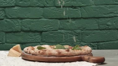 Pizzayola fırında pizzanın üstüne dilimlenmiş sert peynir ekliyor.