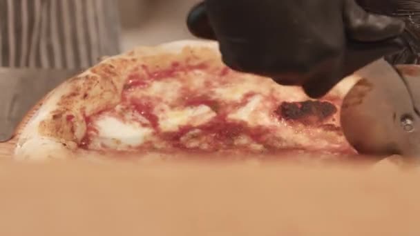Pizzayola rebanando pizza horneada sobre tabla de madera — Vídeos de Stock