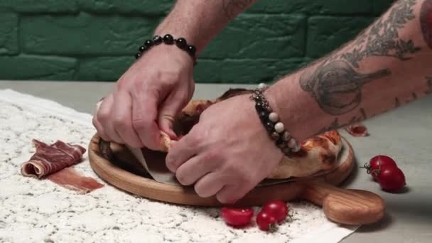 Aproape de un bărbat care rupe pizza proaspăt coaptă cu mâinile goale — Videoclip de stoc