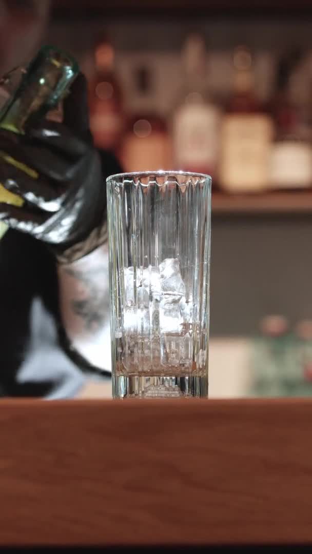 Bartender derramando álcool em vidro com cubos de gelo — Vídeo de Stock