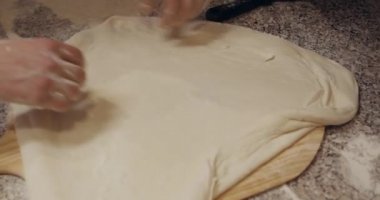 Sıralı pizza hamuruyla çalışan erkeklerin ellerini kapat.
