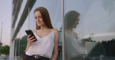 Dışarıda dururken akıllı telefon kullanan mutlu bir kadın.