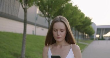 Dışarıda cep telefonundan mesaj yazan güzel bir kadın. 