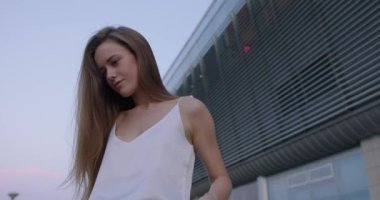 Genç bir kadın açık havada doğal sarı saçlarını düzeltiyor.