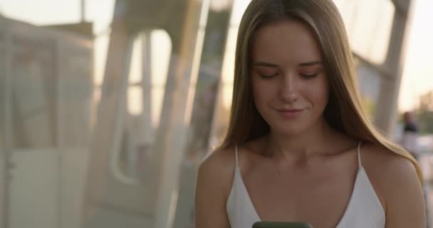 Mujer adorable usando el teléfono celular mientras está de pie al aire libre — Vídeo de stock