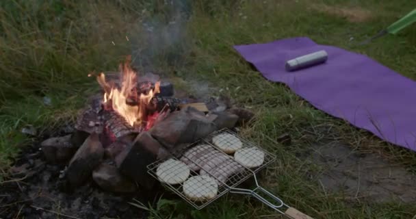 Primer plano de la rejilla de acero conrollos de pan que yacen cerca del fuego — Vídeos de Stock