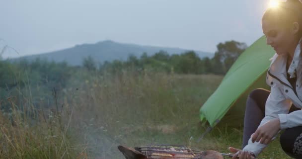 Donna cucinare il cibo sopra il fuoco ardente all'aperto — Video Stock