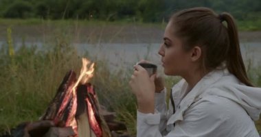 Şenlik ateşinin yanında oturmuş çay içen kadın turist.