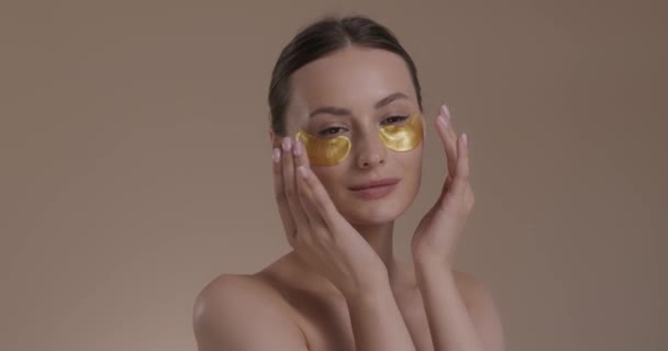 Piękna kobieta stosująca kolagenowe opaski na oczy w studiu — Wideo stockowe