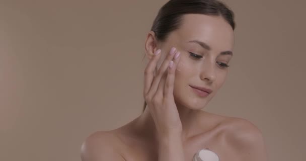 Mulher sensual com ombro nu aplicando creme facial — Vídeo de Stock