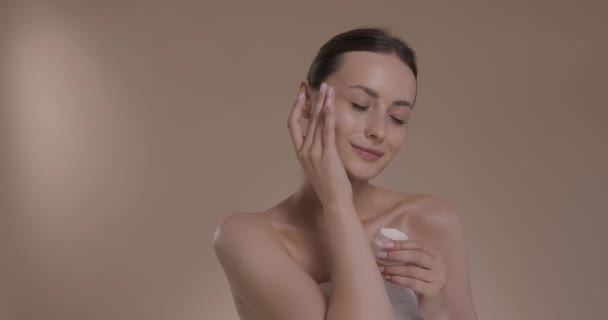 Кавказька жіноча модель застосування зволожувального крему на обличчі. — стокове відео