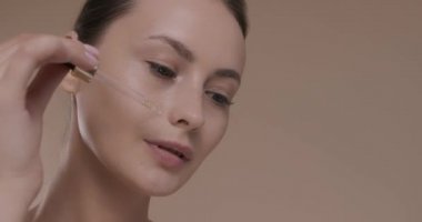 Yüzüne serum süren sağlıklı ve temiz ciltli bir kadın.