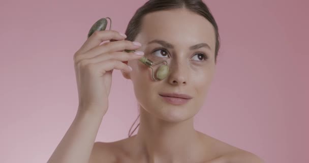 Kobieta robi masaż pod oczami z jadeitowym wałkiem — Wideo stockowe
