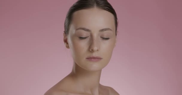 Jovem com os olhos fechados posando sobre fundo rosa — Vídeo de Stock