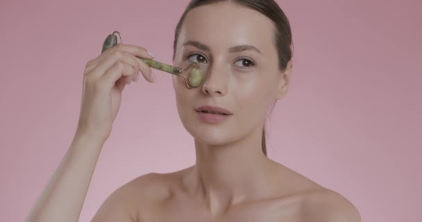 Portret van jonge vrouw masseren gezicht met jade roller — Stockvideo